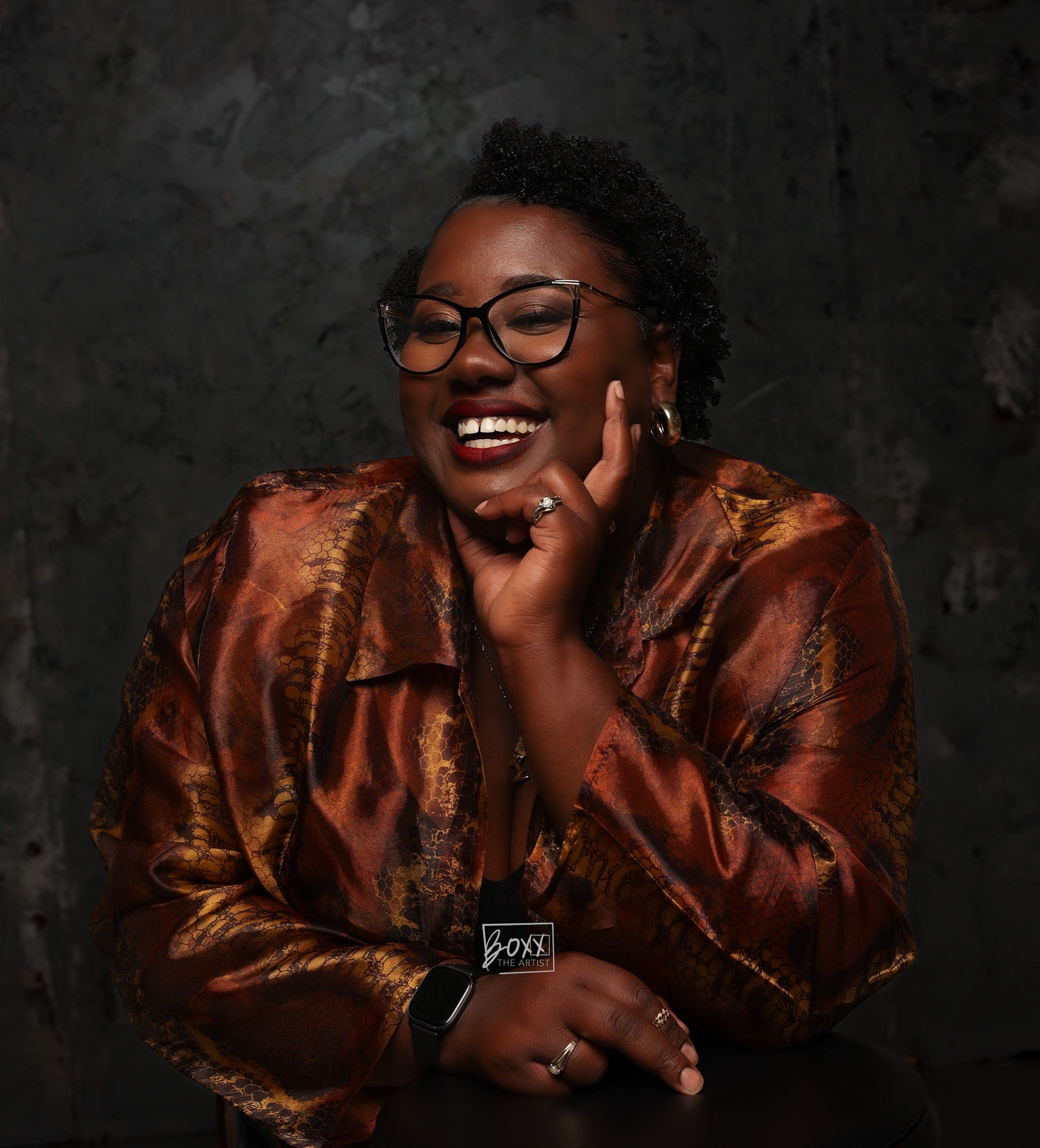 Woman wearing a patterned shirt against a dark background